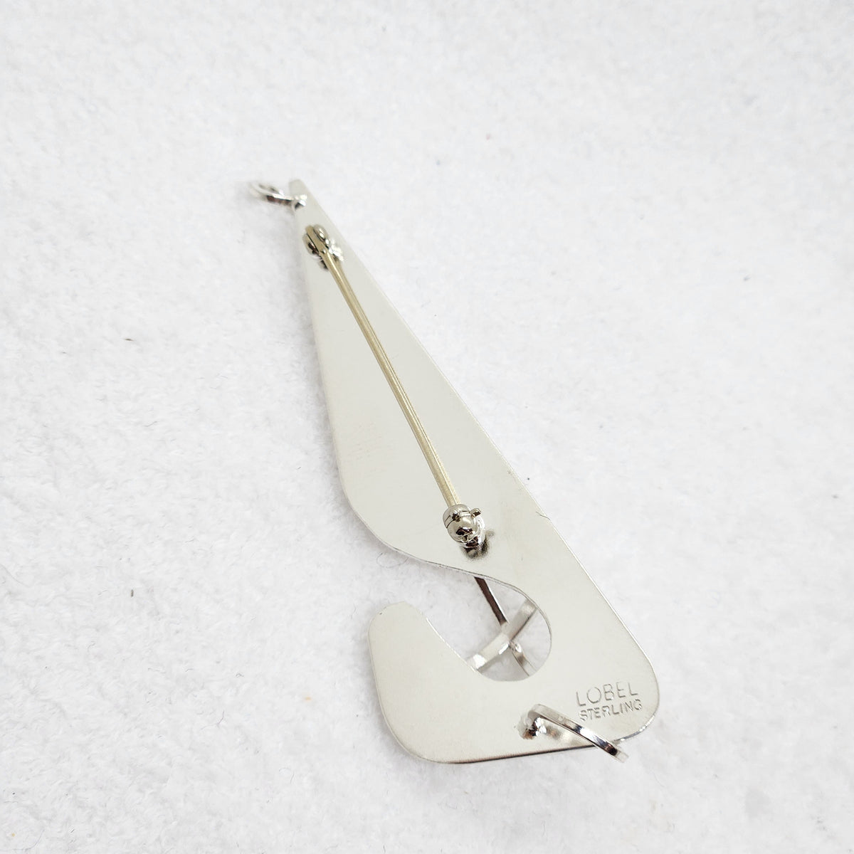A sterling silver teardrop-shaped brooch with a pin-back clasp, featuring the engraved brand name 'LOBEL STERLING' on the lower right edge, displayed on a textured white background.